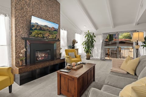Top-floor living room: vaulted ceiling, fireplace, smart TV, deck sliders.