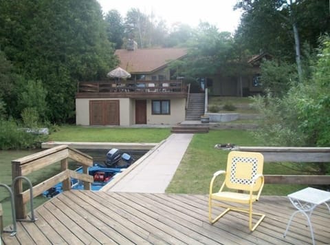 View of house and boat house from dock with fire pit and harbor