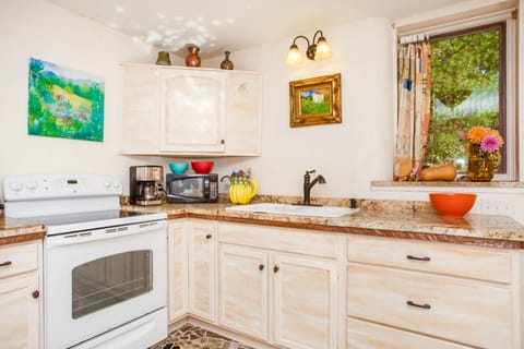 A beautiful kitchen with glorious granite countertops and faux marble cabinets.