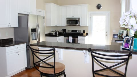 The kitchen features granite counters, custom cabinetry, and seating for 2.
