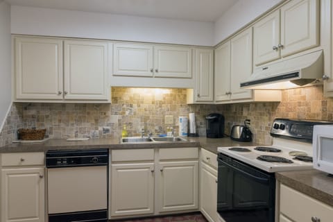 The large kitchen has tile backsplash and hardwood floors.