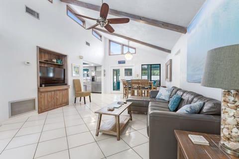 Spacious living room with vaulted ceiling, leather couch, and large Smart TV.