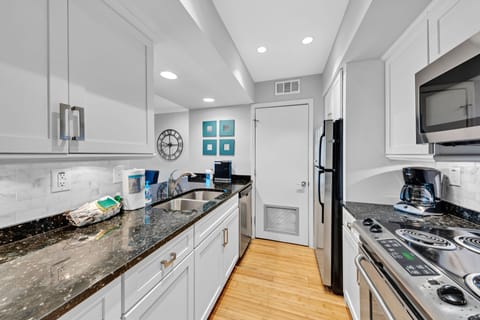 The galley kitchen has granite counters, custom cabinets and stainless steel appliances