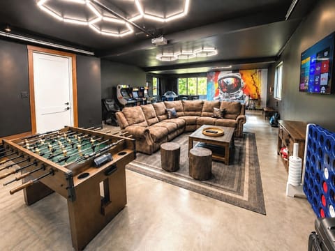 Expansive game room featuring ping pong, air hockey, arcade machines, basketball hoops, and lounge seating