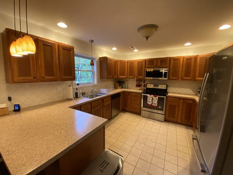 Fully stocked kitchen with pots and pans, dishes and utensils, glasses and cups.