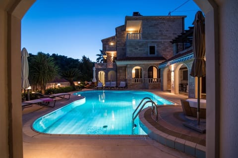 Evening ambiance with illuminated pool and elegant stone villa