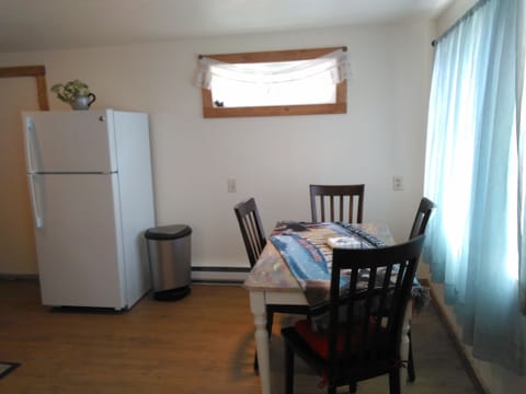 Part of kitchen showing  refrigerator and dining table in front of window.