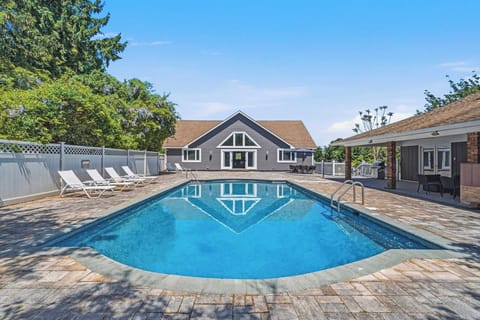 Pool with paver patio, main house, and pool house