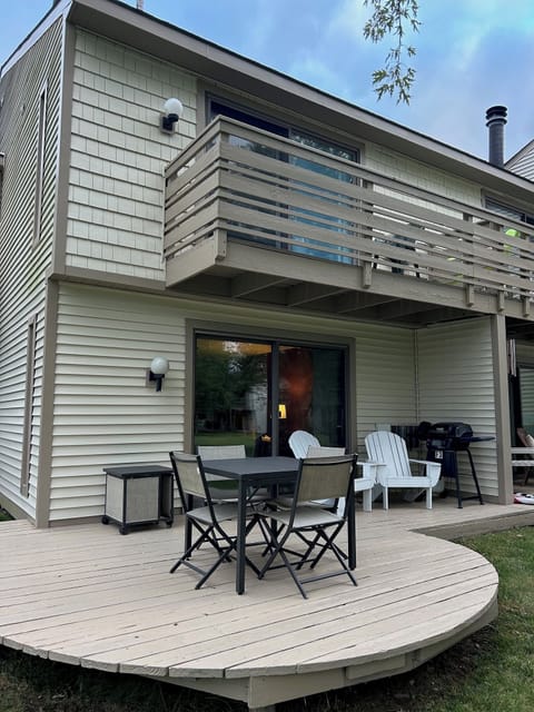 Deck has a patio table with four chairs, two Adirondack chairs, and a gas grill.