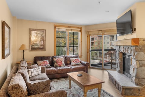 Cozy up on plush sofas by your stone fireplace, watching the wall-mounted TV while autumn views fill the windows. Perfect for relaxing evenings in.