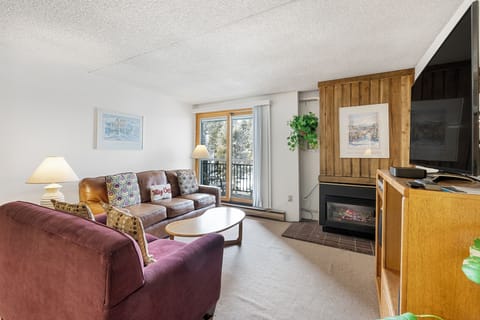 Unwind in your cozy living space with plush seating, warm fireplace glow, and natural light streaming through your private balcony doors.