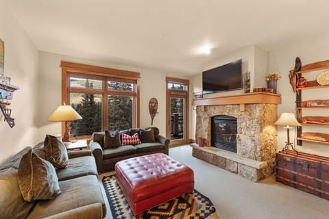 Sink into plush seating by your stone fireplace, where warm wood accents and mountain views create the perfect retreat.
