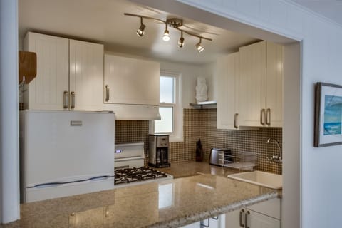 Fully stocked open kitchen with eat-in counter and barstools.