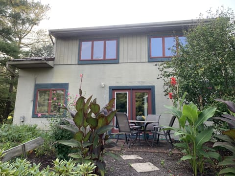 Back patio of the guesthouse with lush gardens, chairs and table. 