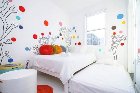 Playful, art-filled bedroom with bright murals, cozy beds, and natural light—clean, fun, and perfect for a cheerful stay.
