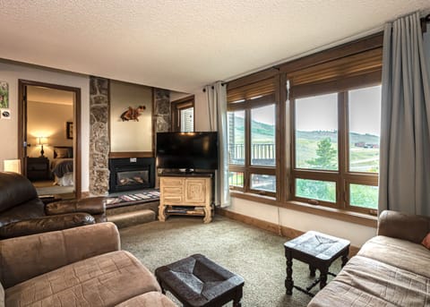 Cozy living room with gas fireplace features couch, recliner, smart TV, and view