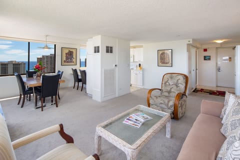 Large open living/dining room with kitchen. Air conditioner for this room (one of three). The recliner has been replaced with a loveseat.