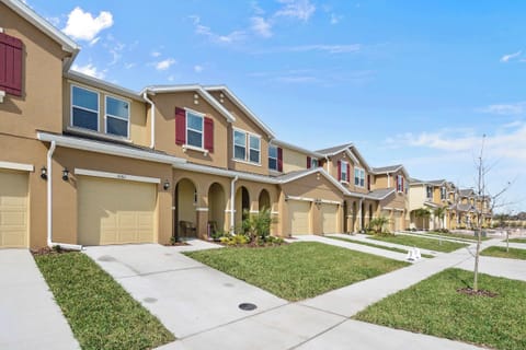 Sunny row of Compass Bay townhomes with warm beige exteriors, archways, and tidy yards-perfect for a bright, family-friendly Florida stay.