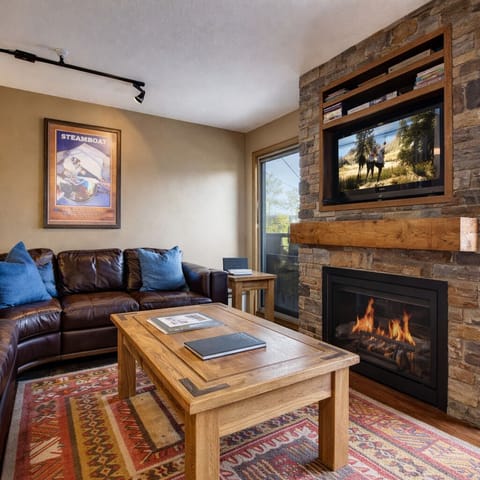 Cozy living room with a stone fireplace, comfy leather sectional, and a large TV. Perfect for relaxing after a day on the Park City slopes.