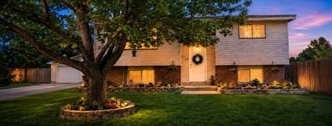 Charming dusk exterior with lush lawn, mature tree, and inviting curb appeal