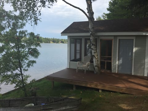 Screened in boat house with loveseat, lounges, and gas fireplace inside