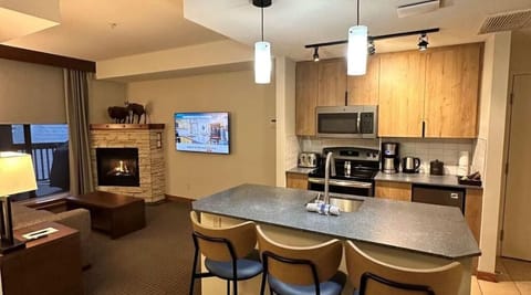 Inviting kitchen and living area with warm wood tones and a cozy fireplace, creating a welcoming atmosphere.
