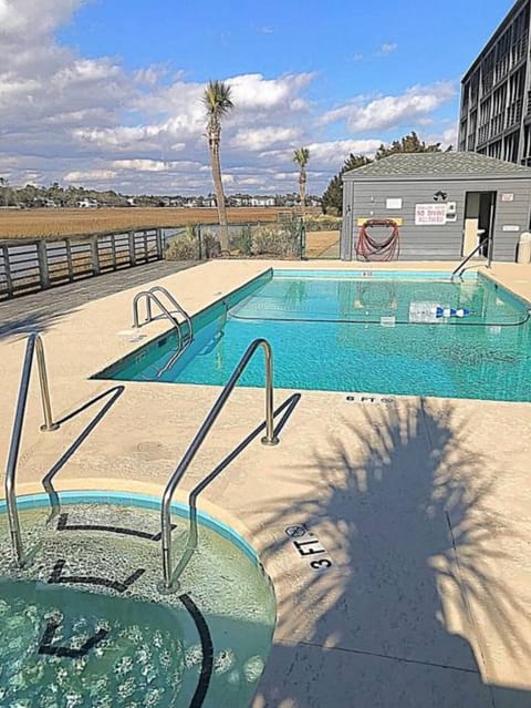 Pool, hot tub, and bath house with a marsh view.
