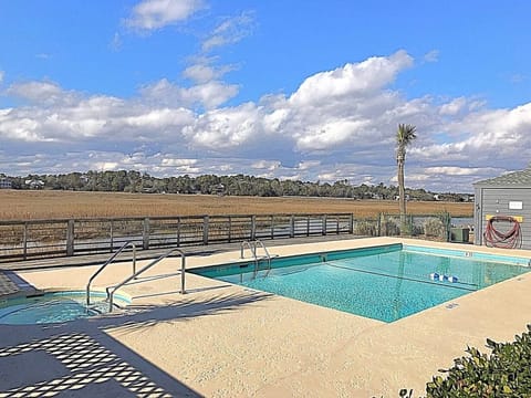 Pool, hot tub, and bath house with a marsh view.