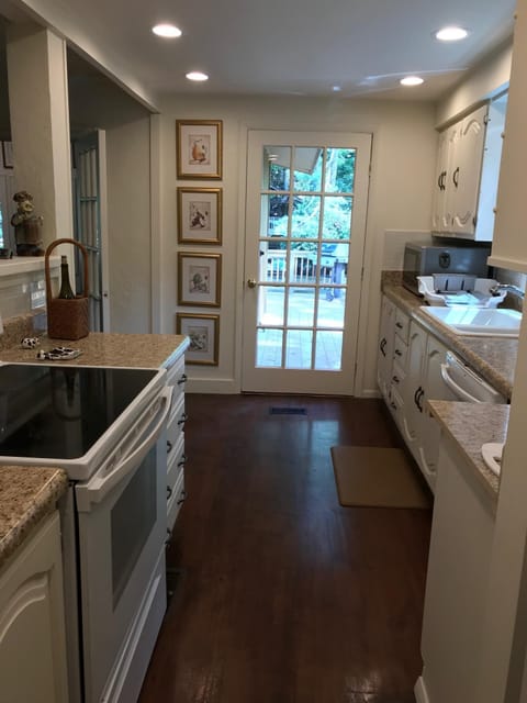 Kitchen door leading to large deck with gas grill and table for 8 with umbrella.