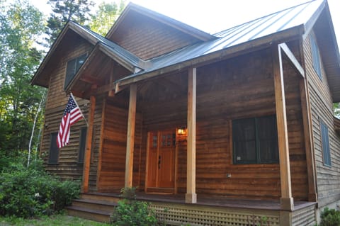 Front of the home in the summer. The home is completely surrounded by forest