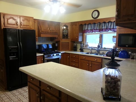 Kitchen stocked with plates, cups, silverware, pots & pans.