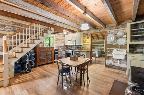 Charming farmhouse-style kitchen with cream cabinets, a vintage sink, glass-front cabinetry, and rustic log walls—blending comfort with classic cabin character.