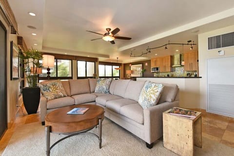 Spacious living room with neutral tones, ceiling fan, and cozy seating.