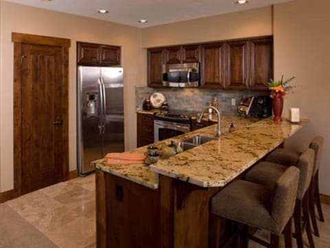 The fully-equipped kitchen features granite countertops, stainless steel appliances and a breakfast bar