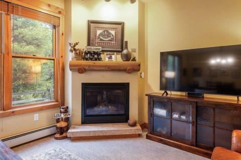 A cozy corner of the living room highlights a view of the fireplace and TV, with large windows allowing natural light to flood the space.