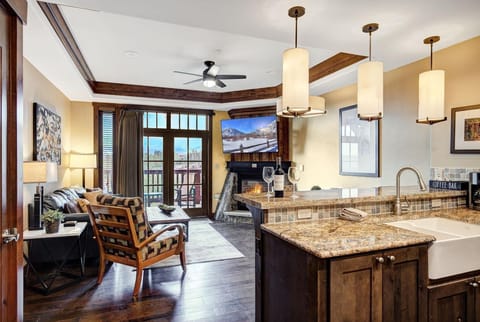 Dark hardwood floors and granite counters contrast with warm wood trim in the open kitchen and living area.