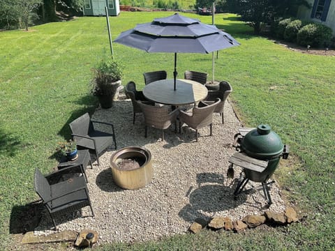 Large grass back yard with seating area, big green egg and firepit