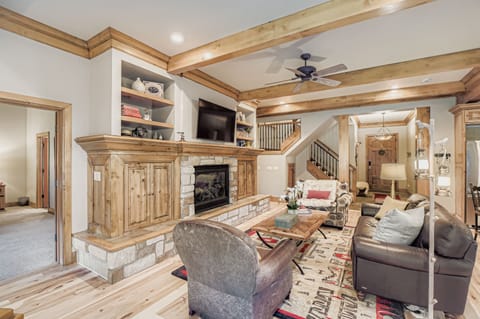 Settle into your cozy living room with warm wood beams overhead, a crackling stone fireplace, and plush seating perfect for relaxing evenings together after a day of mountain adventures.