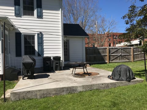 Back patio with grill, table and chairs and fire ring.