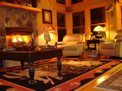 Great room at night, leather sofa, recliners, vaulted ceiling, fireplace, big TV