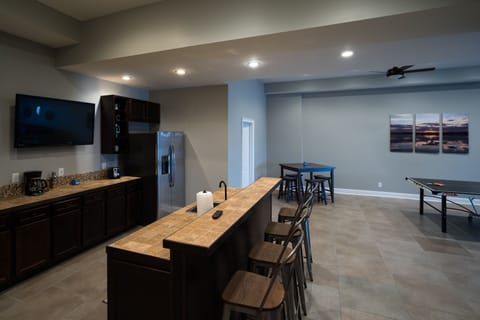 Downstairs bar with 50" TV, fridge, sink and wine glasses