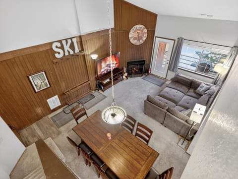 Cozy up in your mountain retreat's spacious living area, where wood paneling and a crackling fireplace create the perfect après-ski atmosphere for relaxing evenings.