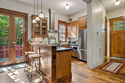 Sleek kitchen with bar seating for two, gas range stove, dishwasher, and drip-style coffeemaker.