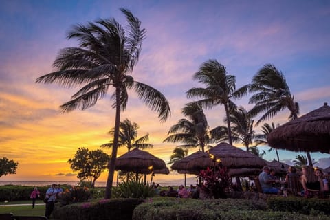Vibrant sunset skies, swaying palms, tiki torches, beachfront dining bliss.