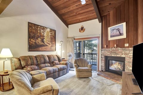 Comfortable living room with a gas fireplace, reclining couch, access to deck
