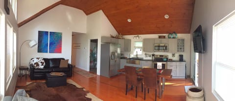 Panoramic view of open concept living area with large wall mount smart TV.