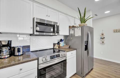 - Cook up your favorites with a stainless steel oven, microwave, and full size fridge - Sleek counters and white cabinetry offer a fresh, functional space for every meal - Whether it’s coffee at sunrise or dinner after the beach, this kitchen has you cover