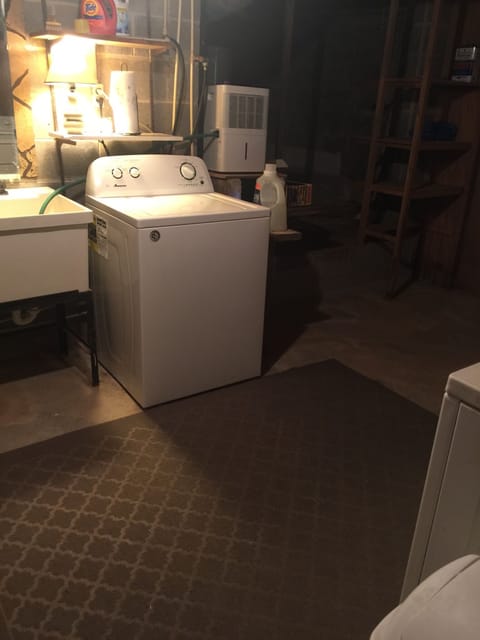 Laundry with sink and washer/dryer in basement. 