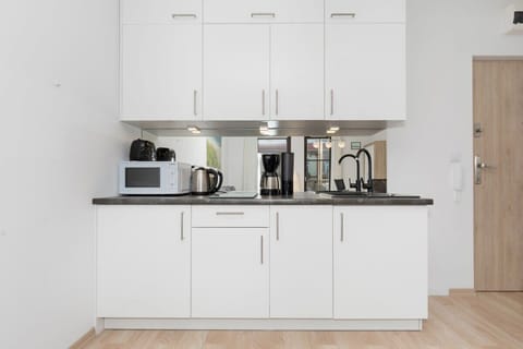 Functional and white kitchenette with a microwave, a kettle, a toaster and a coffee machine.