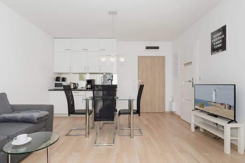 Spacious living room with television, coffee table, kitchenette, dining table and sofa.